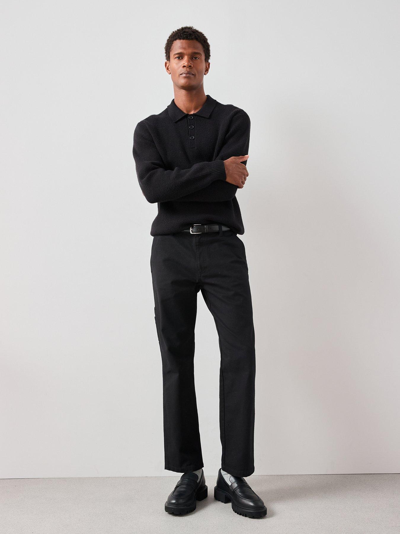 Model wearing an all black smart outfit that consists of a black knitted polo, black straight trousers and black loafers.