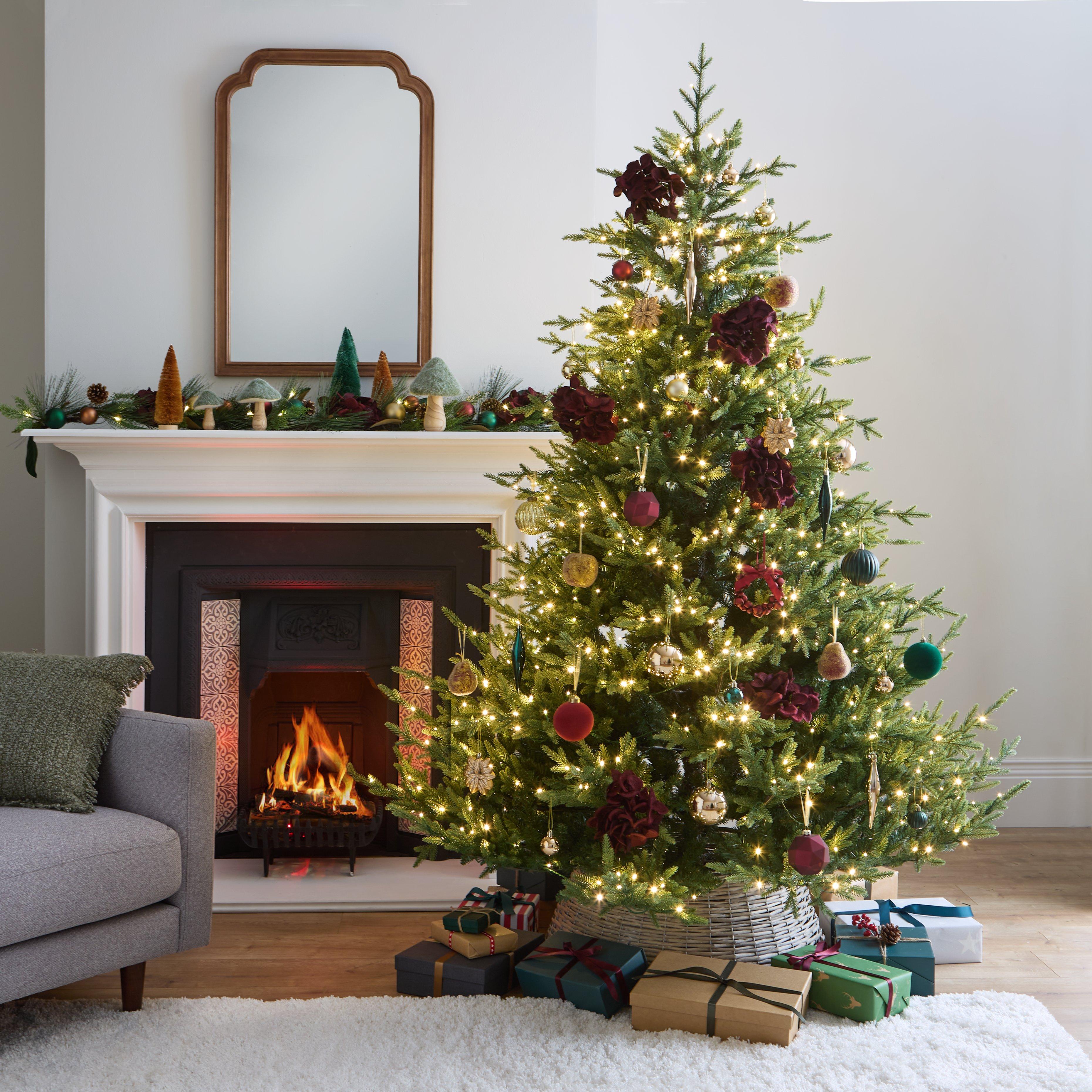 Christmas tree in the living room next to a decorated fireplace. Lots of wrapped presents under the tree