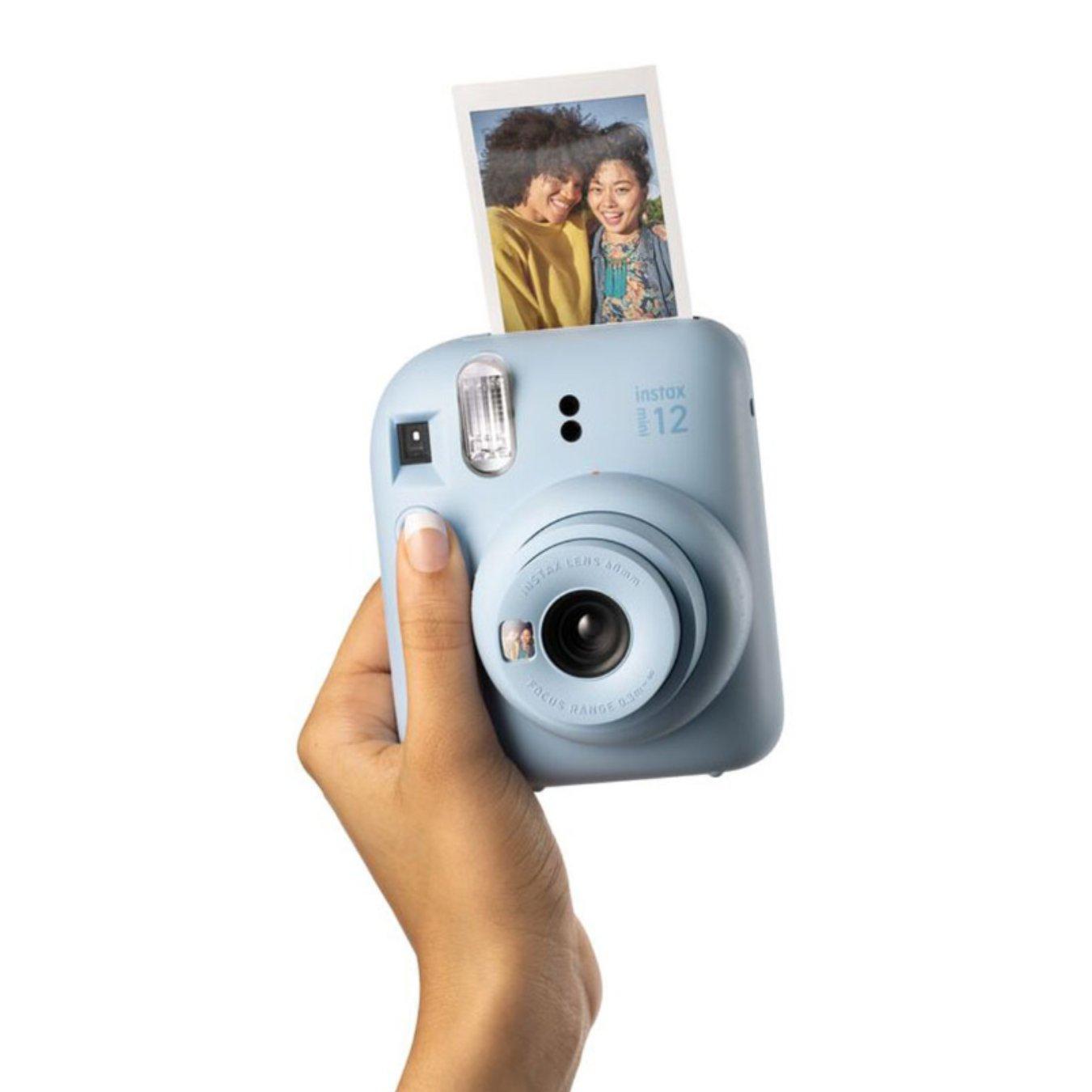 Woman holding a blue Fujifilm Instax Mini 12 Instant Camera as its printing an image