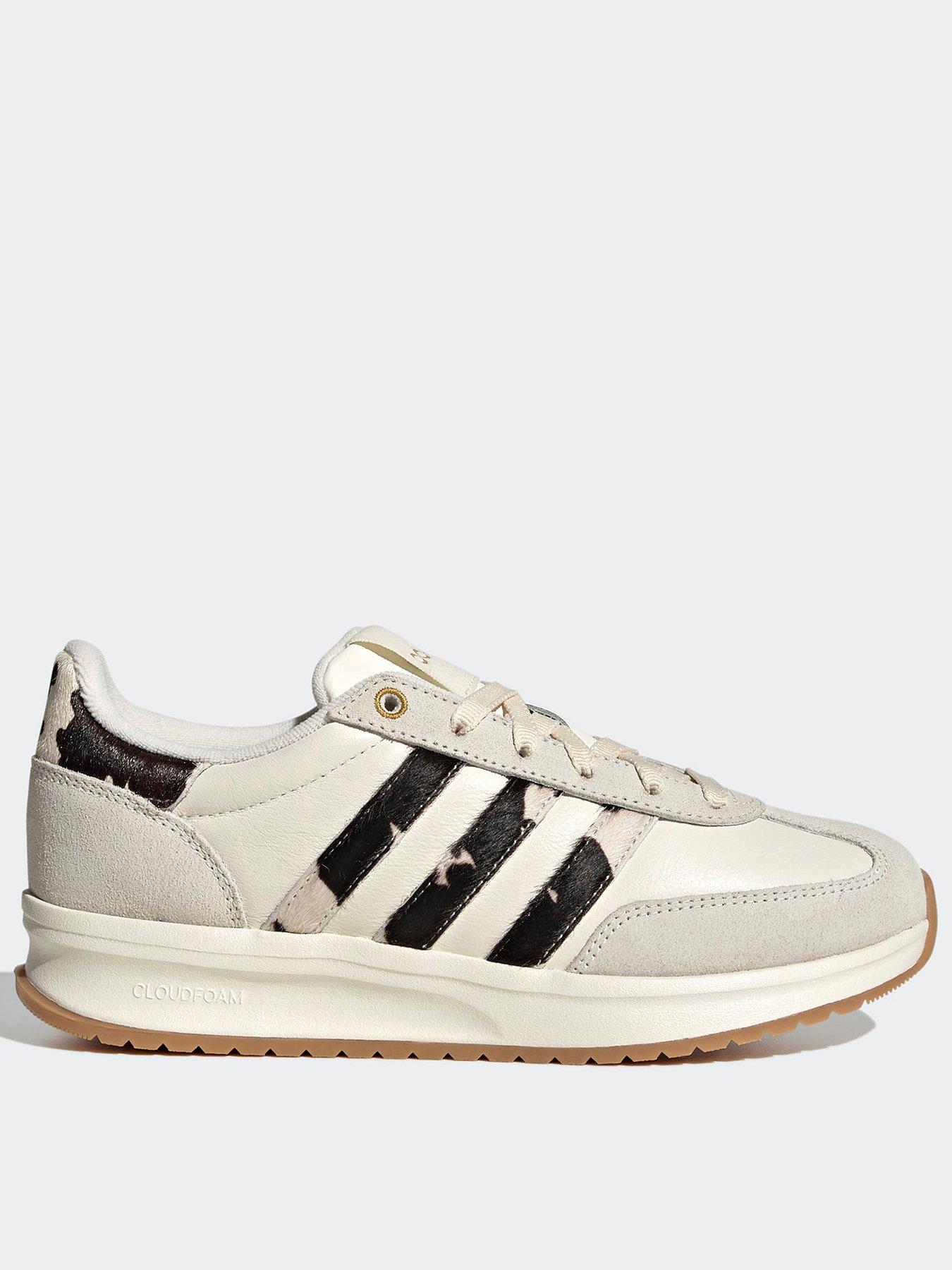 A pair of adidas trainers in cream with a leopard print striped detailing.