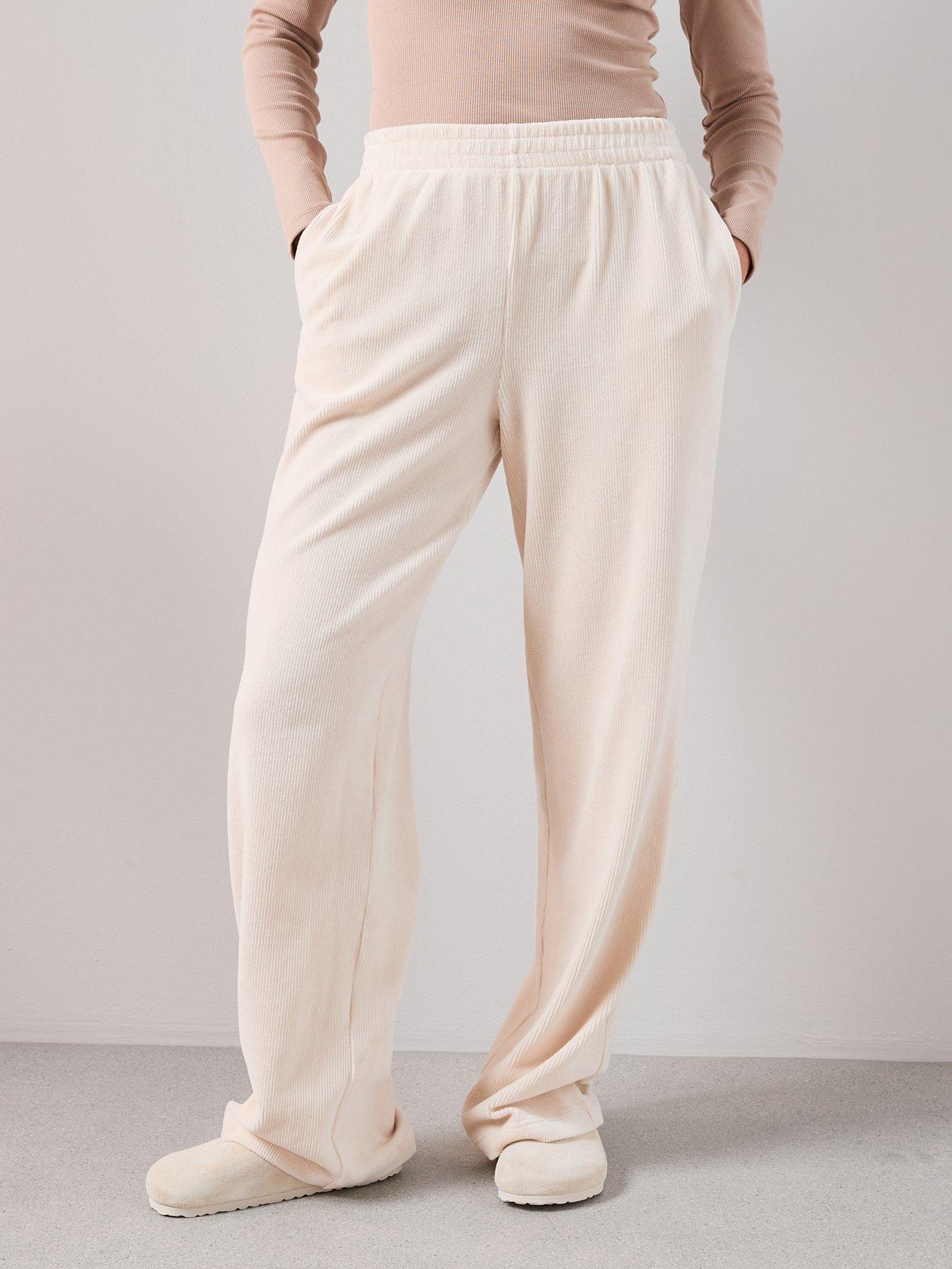 Model wearing a pair of cream wide leg trousers.