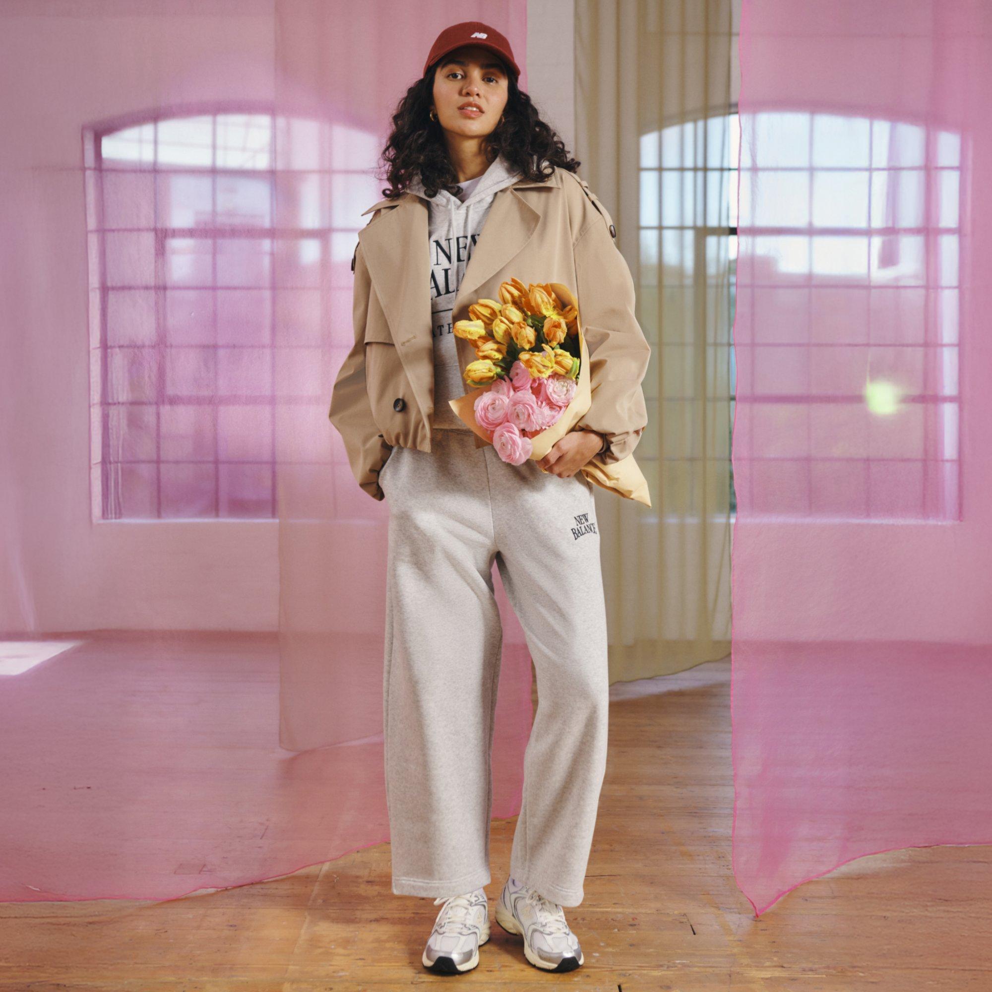 Woman wearing a loungewear set, trainers and a cap holds a big bouquet of flowers. The perfect casual date night outfit.