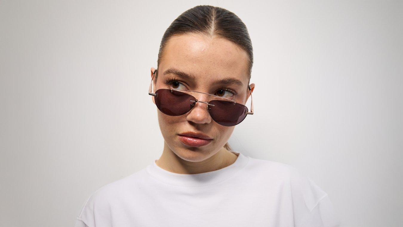 A woman with a heart shaped face wearing a complimentary aviator style sunglasses