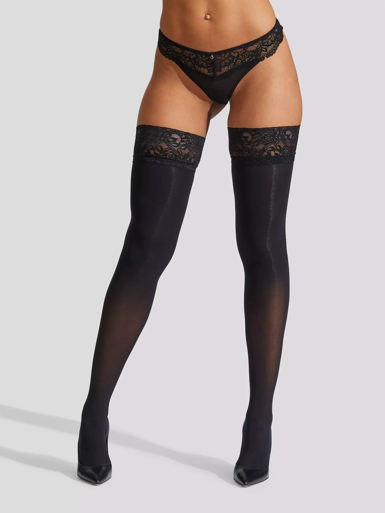 Cropped back view shot of lady's body, wearing black stockings with lace  welt with floral pattern.